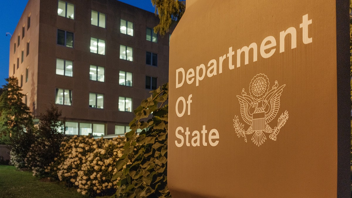 U.S. Department of State headquarters building with illuminated office lights at dusk